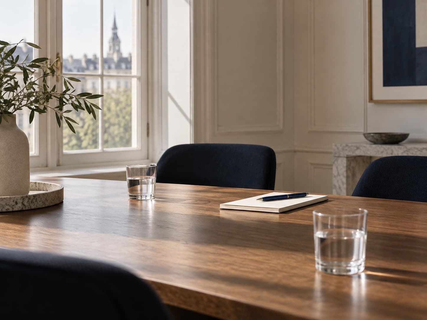 Empty meeting table, two glasses of water, cream notepad