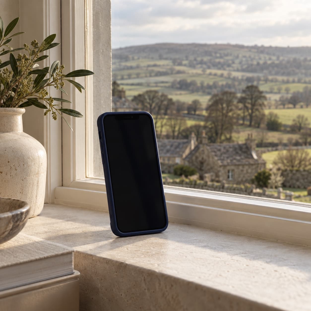 Phone on a cream windowsill, Yorkshire landscape behind the glass