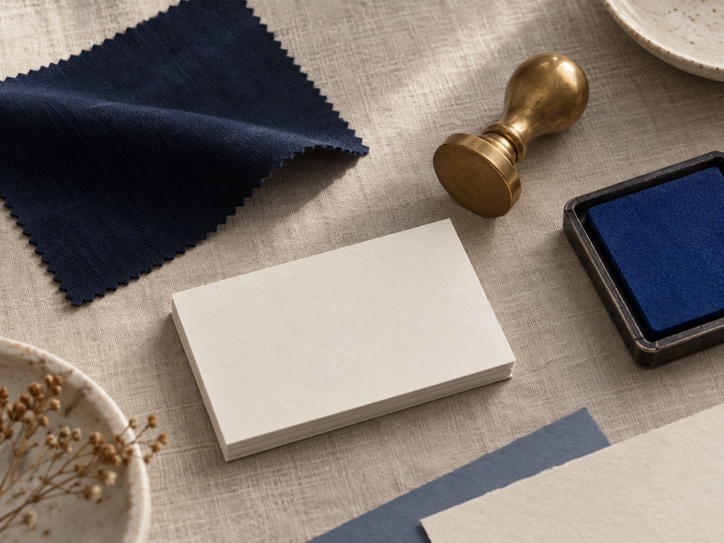 Brand kit still, cream paper, navy swatch, brass stamp